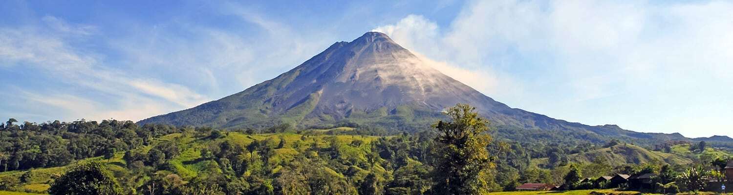 The Arenal Volcano rising above green farmland and forest