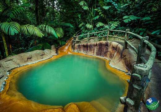 A turquoise hot spring pool in the rainforest near the Arenal Volcano